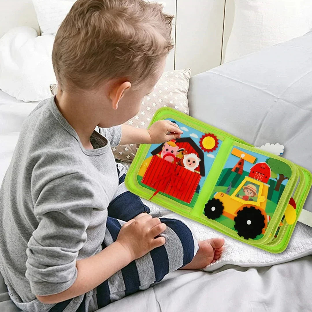 Un copil mic răsfoind cu interes paginile colorate ale cărții senzoriale Kinderspeech „Az én első farmom”, o jucărie educativă interactivă care dezvoltă motricitatea fină prin elemente tactile precum nasturi și fermoare