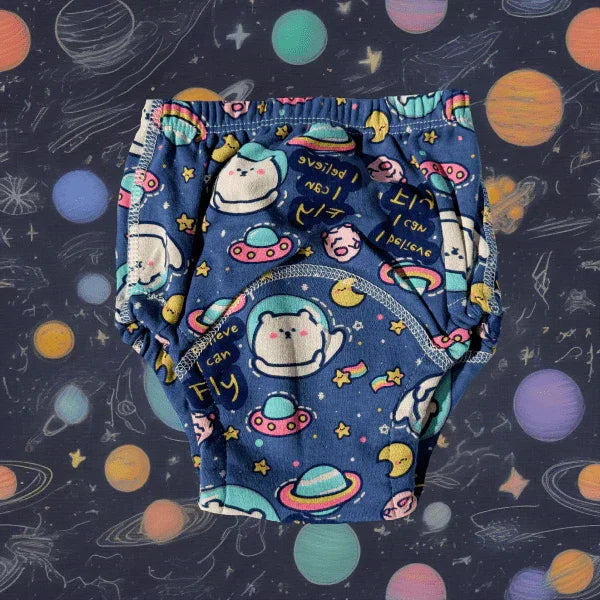 O pereche de chiloței de antrenament pentru copii, de culoare bleumarin cu imprimeu vesel de inspirație spațială, prezentând astronauți simpatici, planete și textul „I can fly”, așezați pe un fundal decorativ asortat cu motive galactice